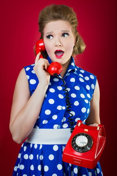 50s style housewife gossiping in a red vintage phone