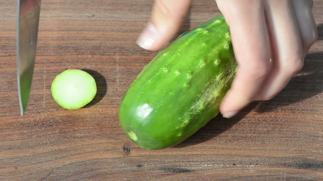 woman hand cut chop green ecologic cucumber knife wooden board
