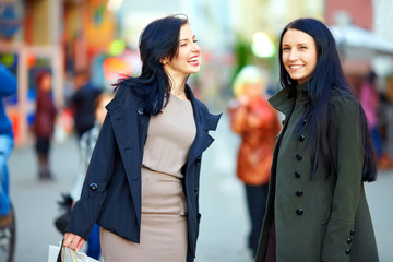 happy female friends walking the crowded city street