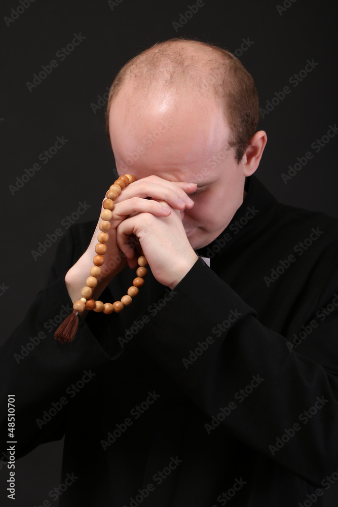 Wall mural young pastor with wooden rosary, isolated on black - Wall murals