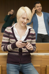 Zwei Studentinnen und ein Student telefonieren und schreiben SMS