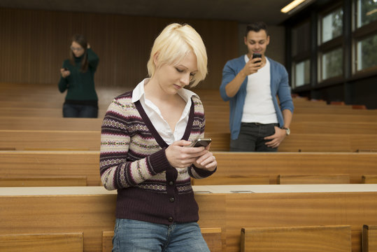 Zwei Studentinnen und ein Student telefonieren und schreiben SMS