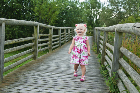 A little girl goes on a wooden bridge