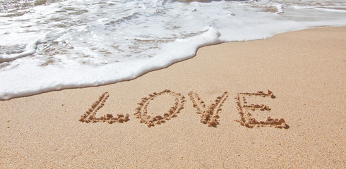 The word love in the sea on the beach in Valentine Day. Closeup.