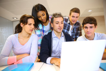 Teacher with students in class working on laptop