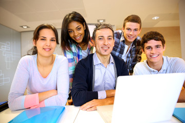 Teacher with students in class working on laptop