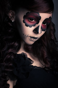 Portrait of young woman with sugar skull make-up . Dramatic ligh