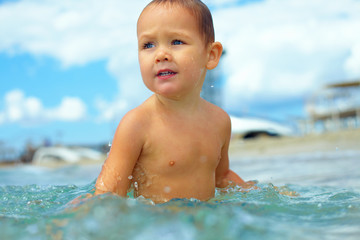Fototapeta na wymiar cute baby boy having fun in sea water