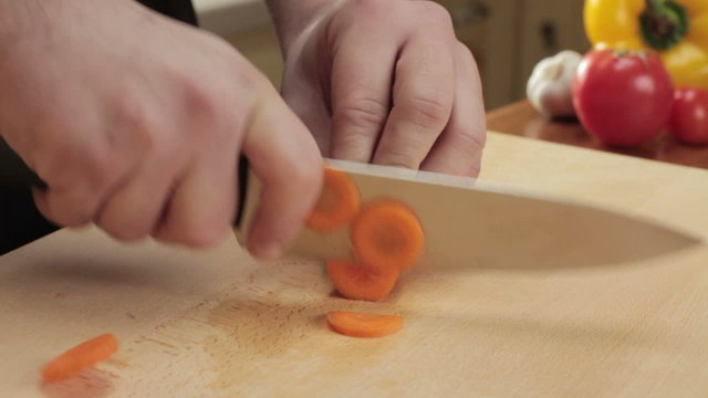 Chef cutting up carrot with a knife, slow motion