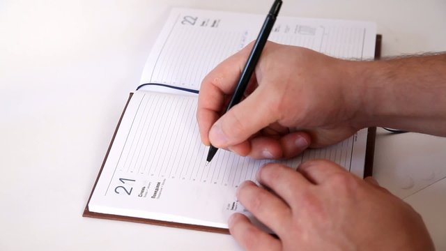 Man writing information in agenda book