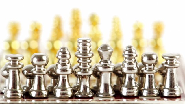 Small golden and silver chess figures in start position