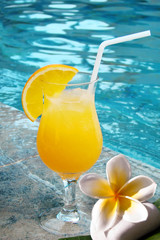 Jus de fruit orange au bord d'une piscine
