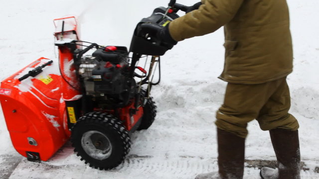 man cleans snow with small manual machines