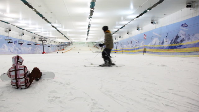 small boy with snowboard prepares for training in sport center