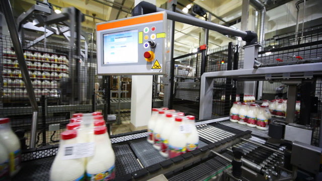 rows of package plastic bottles with milk at factory
