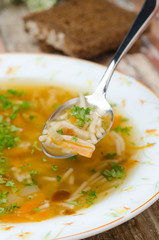 spoon of chicken soup with noodles and carrots closeup vertical