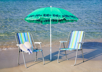 two beach chairs and the beach umbrella on the sea shore - beach