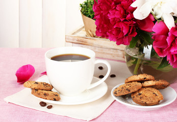 cup of coffee, cookies and flowers on table in cafe