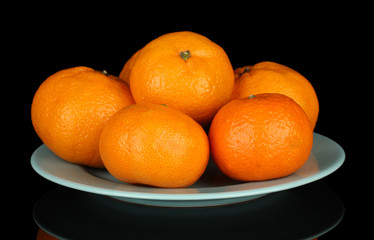 Tasty mandarines  on color plate isolated on black