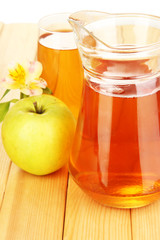 Full glass and jug of apple juice and apples on wooden table