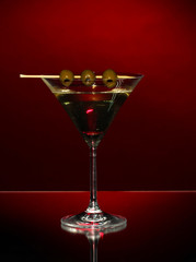 Martini glass and olives on dark background