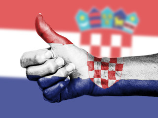 Old woman with arthritis giving the thumbs up sign, wrapped in f