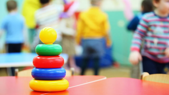 toy pyramid stands on table, in defocus behind it children play