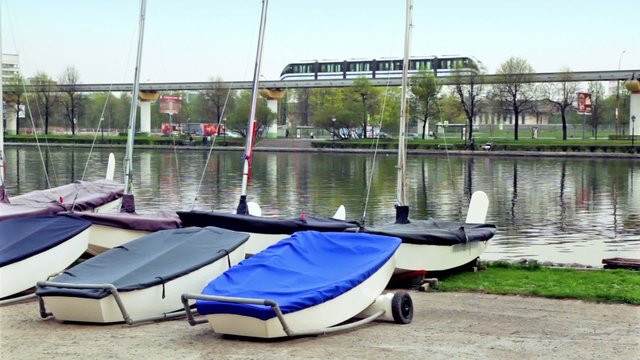 Several boats lay near pond,city traffic on background