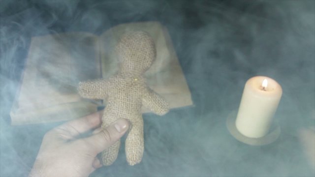 Sorcerer voodoo doll with a pin pierces in the smoke