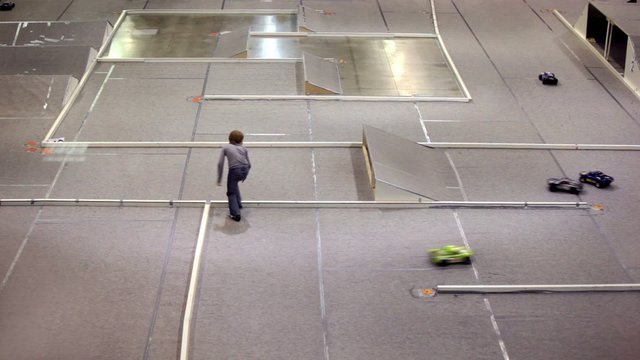 Toy cars ride on track and turns over, boy comes and put it back