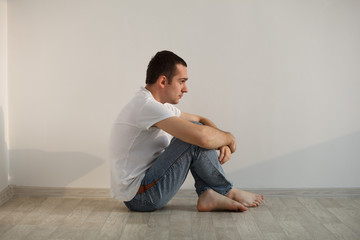 Handsome young man sitting on floor