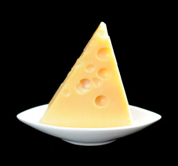 Piece of cheese on a dish isolated on a black background