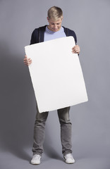 Pleased man holding white blank signboard.