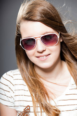 Naklejka premium Pretty brunette teenage girl with sunglasses. Studio shot.
