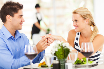 young man putting engagement ring on his girlfriend