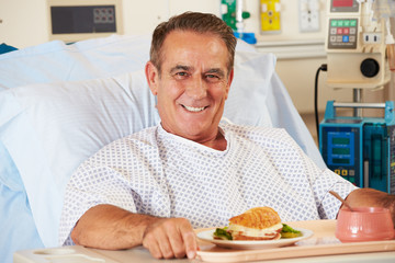 Male Patient Enjoying Meal In Hospital Bed