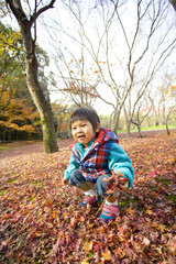 落ち葉で遊ぶ子供