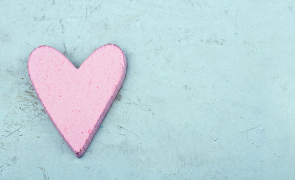 Single pink heart on light blue wooden background