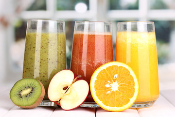 fresh fruit juices on wooden table, on window background