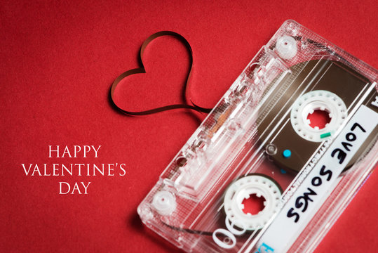 audio cassette with tape in shape of heart on red background