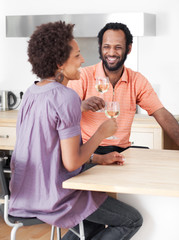 Couple dating, laughing and drinking white wine in their kitchen