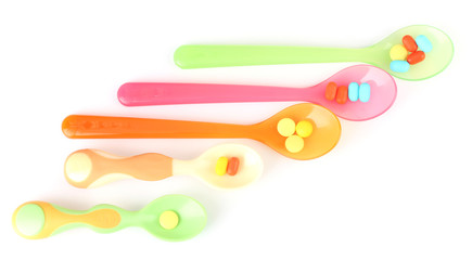 Plastic spoons with color pills, isolated on white