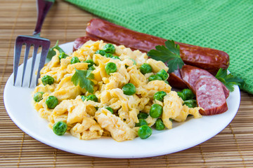 Scrambled eggs with fresh green peas and sausage