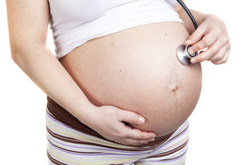 pregnant woman listening her belly with stethoscope