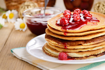 Delicious pancakes with raspberries on the wooden kitchen  table