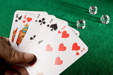 Spielkarten und Spielwuerfel auf gruenem Grund