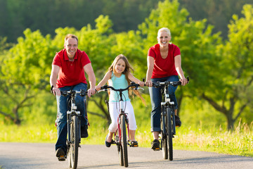 Family with kid cycling in summer with bicycles