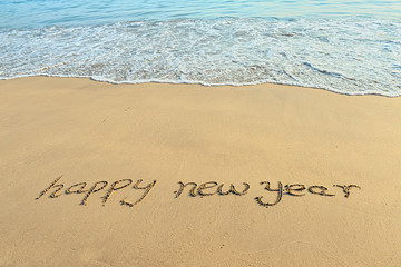 happy new year written in the sand
