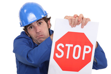 builder in jumpsuit holding stop sign