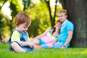 baby playing with parents in a beautiful summer park